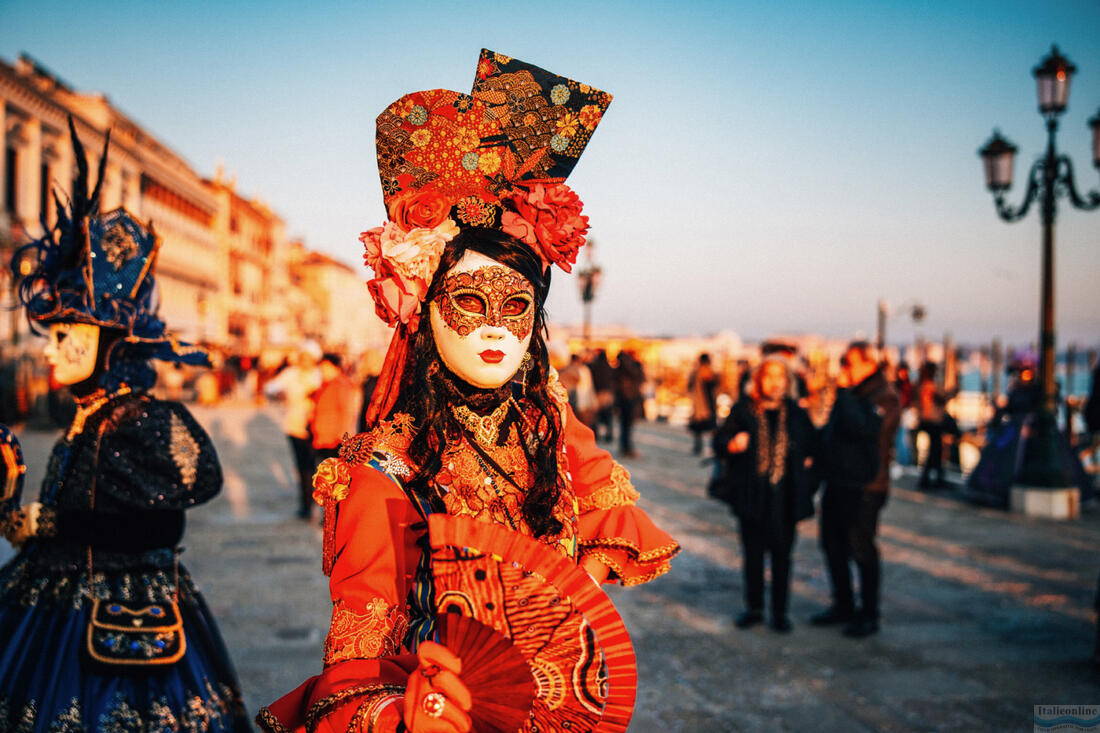 Krásná žena v červeném kostýmu a tradiční masce během Benátského karnevalu, 2023