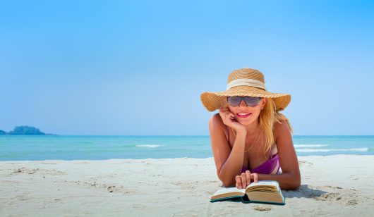 Молодая женщина читает на пляже